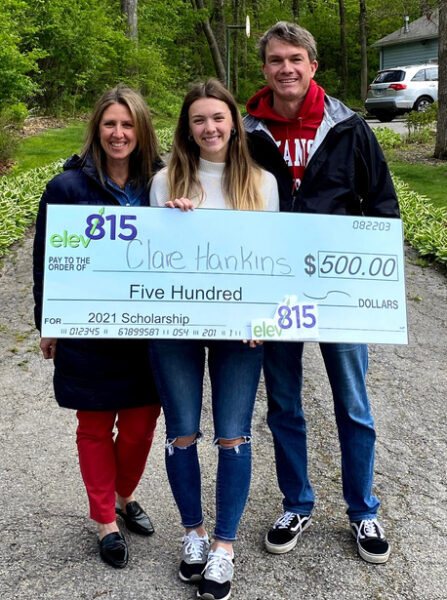 Scholarship winner with parents on their driveway, holding giant check